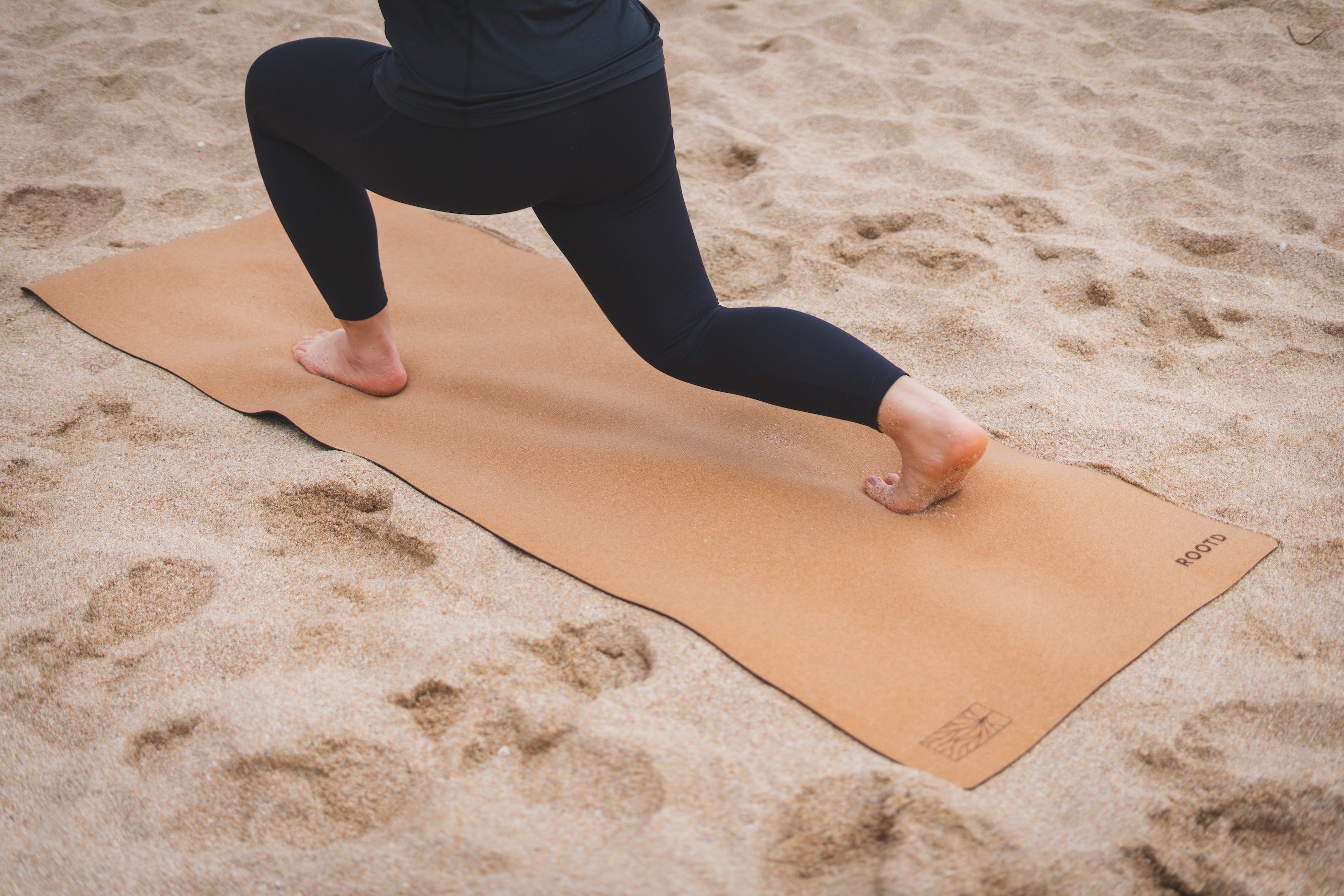 ROOTD elite mat non-toxic eco cork exercise mat yoga mat bare design beach plain. Woman doing lunches at the beach.