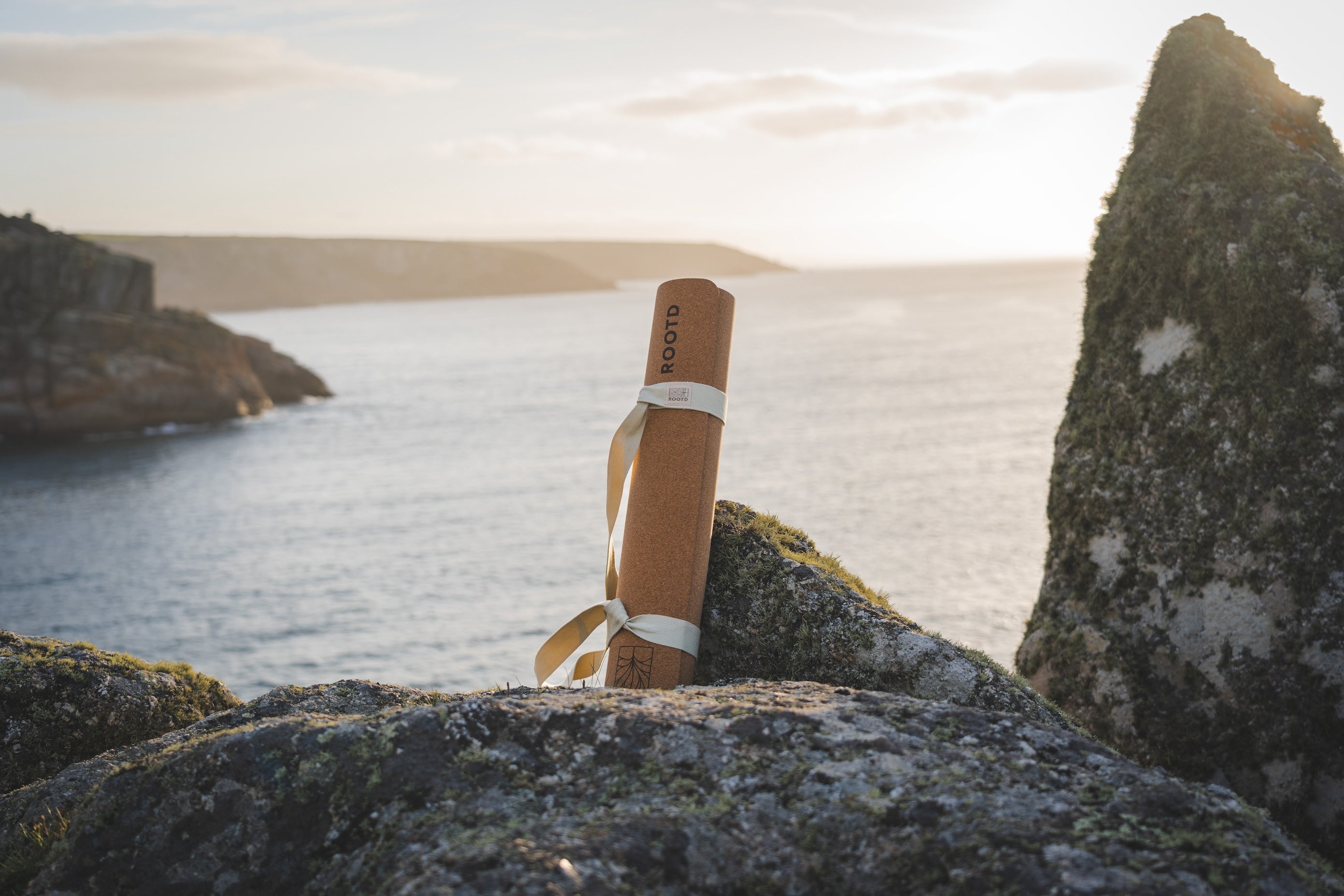 ROOTD elite mat non-toxic eco cork exercise mat propped against a rock at sunrise 