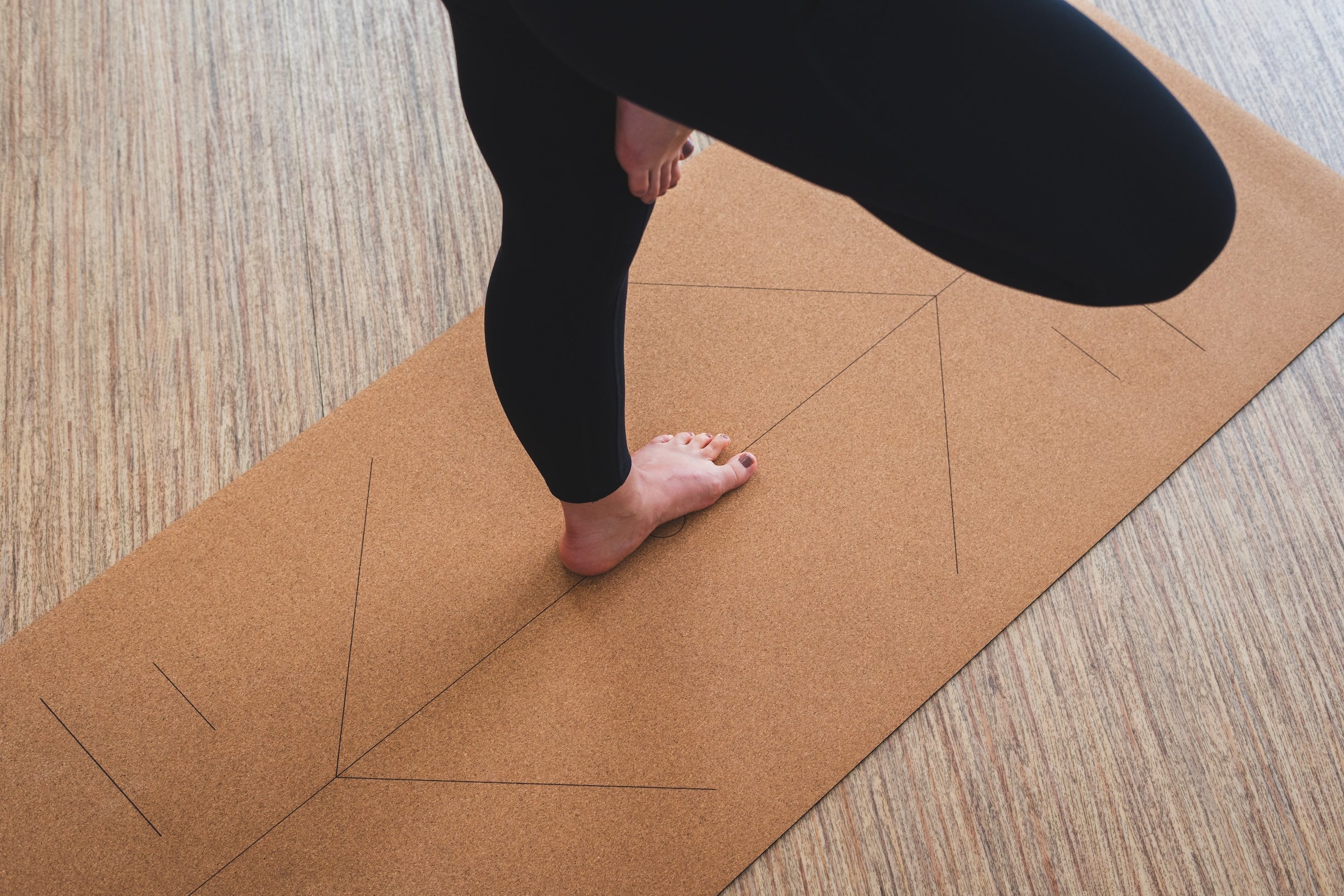 ROOTD Elite Elite Align Design. Non-toxic eco cork exercise mat being used in a gym setting with alignment lines and tree pose during yoga practice.