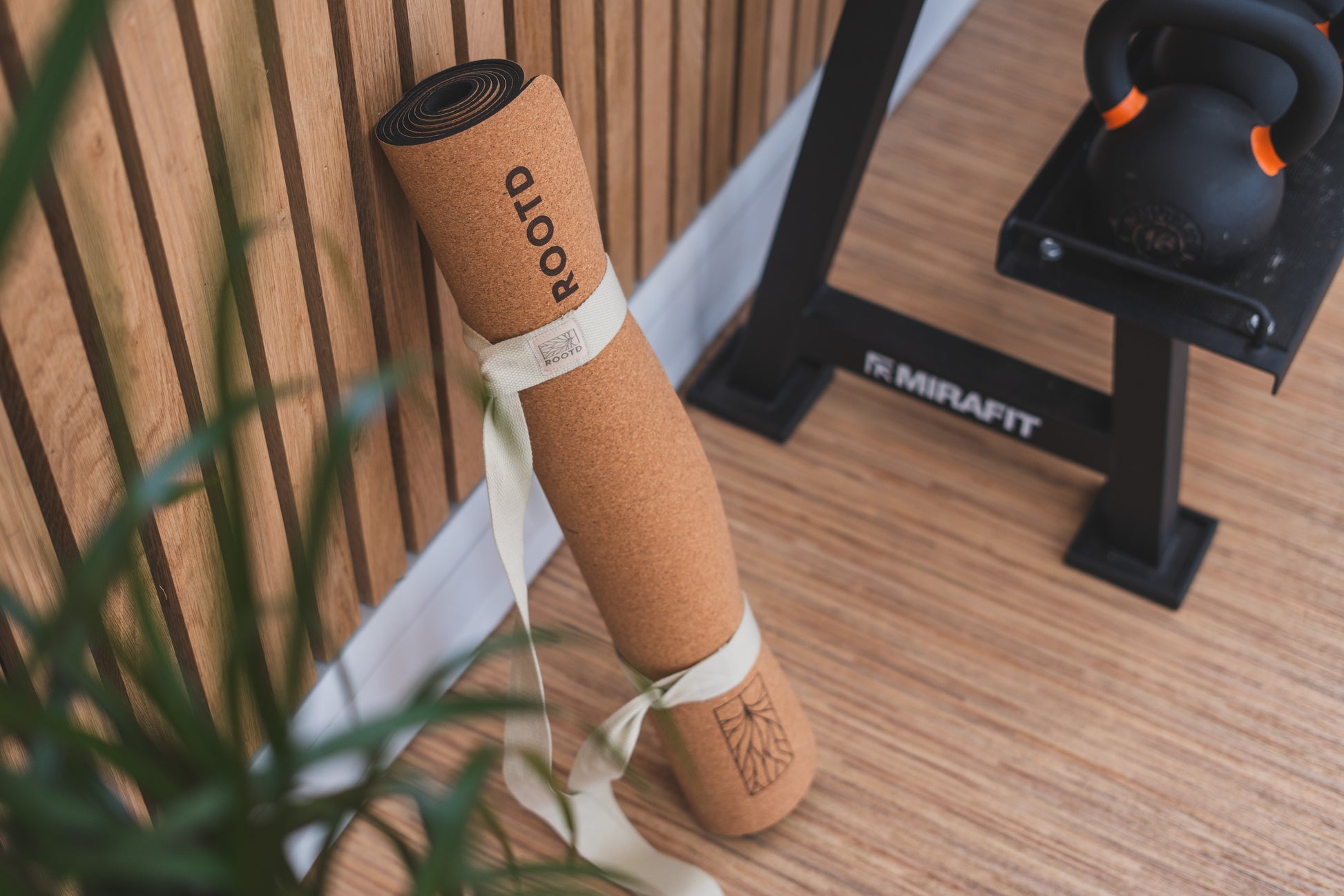 ROOTD Elite Align Design. Non-toxic eco cork exercise mat with alignment lines in a gym setting. Rolled up with a white cotton carry strap. 